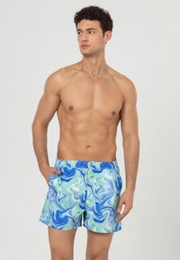 Zwemshorts met een blauw en groen draait een marmerpatroon. Gemaakt van lichtgewicht materiaal met een elastische tailleband en zijzakken.