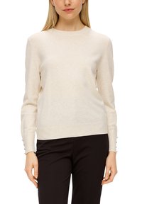 Crèmefarbener Pullover mit rundem Ausschnitt, langen Ärmeln und Knopfdetails an den Bündchen. Weiches Strickmaterial, schmaler Schnitt.