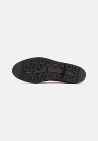 Black rubber sole with textured pattern, featuring horizontal and vertical grooves. Designed for traction and durability.