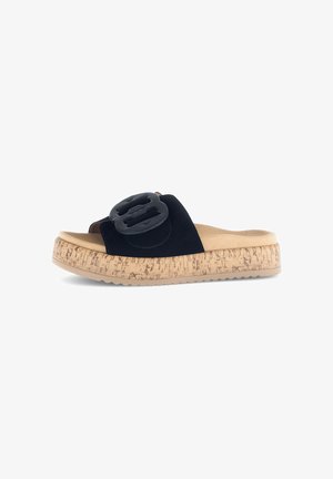 Zwarte suede slip-on sandalen met een grote zwarte gespsluiting, kurk-textuur middenzool en rubberen zool. Vlakke, open teenontwerp voor gemakkelijk aan- en uittrekken.