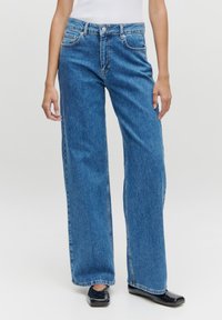 Blauwe denim wijde broek met hoge taille, twee voorke pockets en een vervaagde textuur. Afgewerkt met een knoop- en ritssluiting.