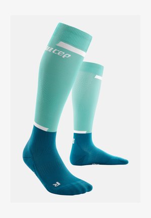 Calze a compressione alte fino al ginocchio color verde menta con accenti in teal scuro, texture a coste e branding bianco nella parte superiore.