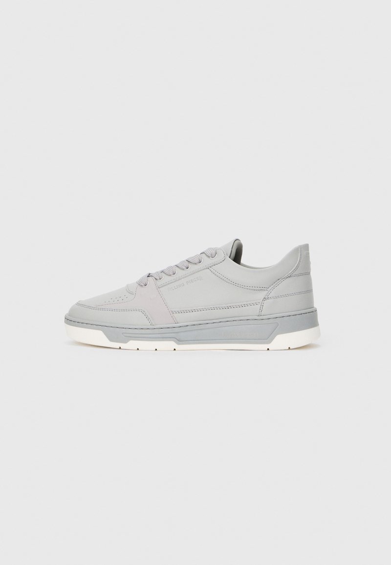 Baskets gris clair en cuir lisse avec une texture subtile. Elles présentent des lacets ronds, un logo en relief et une semelle en caoutchouc blanche.