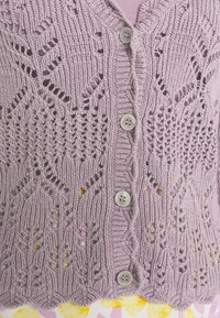 Ljuslila stickad cardigan med ett spetstyg, fem knappar och ribbad kant. Det texturerade tyget skapar en intrikat design.