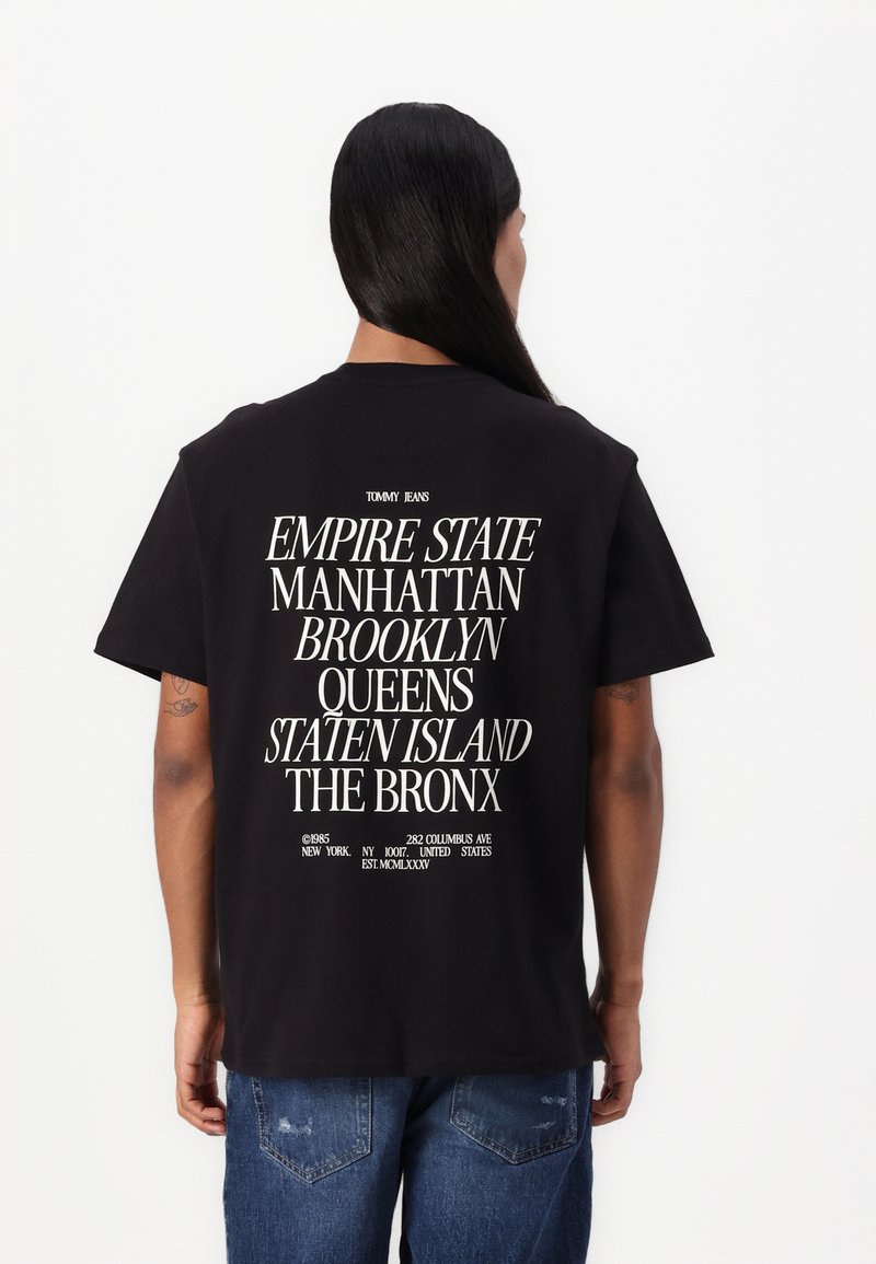 Sort bomulds t-shirt med stort hvidt tekst på ryggen med bynavne og brandlogo. Kortærmet og rund halsudskæring.
