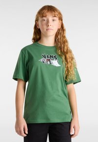 Grünes Baumwoll-T-Shirt mit kurzen Ärmeln und Rundhalsausschnitt. Auf der Vorderseite befindet sich ein grafisches Design eines Autos und Rampen in Schwarz-Weiß.