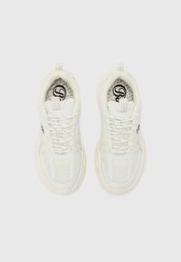 White sneakers with a mesh and leather upper, thick sole, and lace closure. Notable branding on the insole and heel tab.