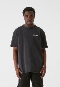 Sort oversized t-shirt lavet af bomuld, med rund halsudskæring og korte ærmer. Inkluderer hvidt broderet logo på venstre bryst.