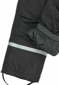 Musta takin hiha, jossa on joustava hihansuu ja harmaa heijastava raita. Materiaali näyttää sileältä ja mattaisen pinnan omaavalta.