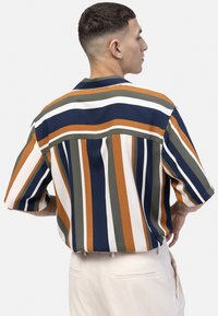 Kortärmad skjorta med djärva, vertikala ränder i marinblått, orange, grönt och vitt. Har en krage och en avslappnad passform, tillverkad av lätt tyg.