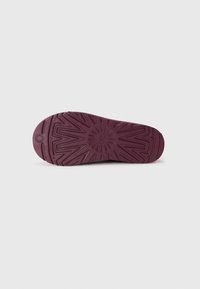 Semelle en caoutchouc violet avec un motif texturé, présentant des rainures et une forme circulaire pour une meilleure adhérence et traction.