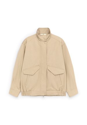 Smėlio spalvos bombonešio stiliaus striukė su stovinčiu apykakliu, spaustukais užsegami suktukai, elastine apačia ir dviem priekinėmis kišenėmis su atvartais ant balto fono.