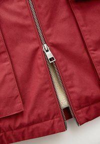 Jachetă burgundy cu un fermoar metalic, având un căptușel moale de crem. Designul include buzunare laterale și o textură de țesătură netedă și mată.