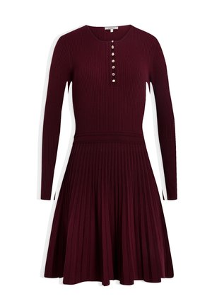 Bordeaux ribbeljurk met lange mouwen, voorzien van een ronde hals en een knoopsluiting. De rok is geplooid met een getailleerde taille.