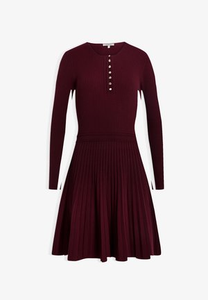 Abito a coste bordeaux con maniche lunghe, dotato di scollatura rotonda e patta con bottoni. La gonna è a pieghe con vita aderente.