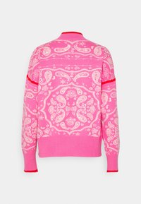 Pull rose avec motifs paisley et floraux blancs, poignets et ourlet côtelés, et fines rayures rouges sur les manches et le col.