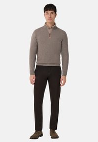 Ljusbrun pullover med halvdragkedja, parat med mörkbruna byxor och mockaskor. Mjuk textur och åtsittande design.