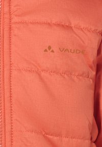 Korálovo sfarbená prešívaná bunda s logom VAUDE umiestneným blízko vertikálneho zipsu na ľavej strane.