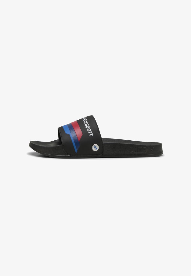 Svarta slidesandaler med en bred rem som har röda, blå och vita ränder och texten "Motorsport". Platt, slät sula med logotypaccenter.
