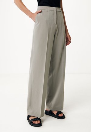 Lichtgrijze wijde broek met hoge taille, gemaakt van een zachte stof. Gecombineerd met zwarte gevlochten sandaal, staand tegen een neutrale achtergrond.