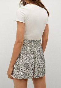 Top blanco de manga corta con textura acanalada, combinado con una falda de patrón floral en blanco y negro, que cuenta con una cintura elástica y un corte acampanado.