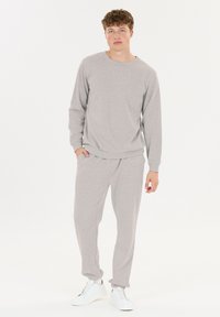 Grau Sweatshirt und passende Jogginghose aus weichem Material, mit entspannter Passform, gerippten Bündchen und elastischem Bund, kombiniert mit weißen Sneakern.