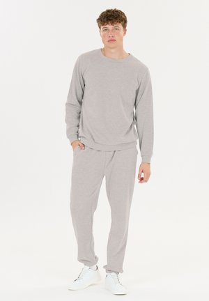 Grijze sweatshirt en bijpassende joggers gemaakt van zachte stof, met een ontspannen pasvorm, geribbelde boorden en een elastische tailleband, gecombineerd met witte sneakers.
