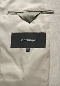 Beige Jackeninnenfutter mit einem schwarzen Textillabel der Marke "Matinique", Größenetiketten EUR 50 und USA 40 sowie einer Tasche.