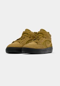 Baskets montantes en daim jaune avec semelles en caoutchouc noir et lacets, présentant une texture lisse et un logo swoosh sur le côté.