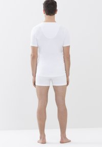 Weiße figurbetonte Kurzarm-T-Shirts und passende Boxershorts, die eine glatte Textur und ein minimalistisches Design zeigen. Der Stoff scheint leicht zu sein.
