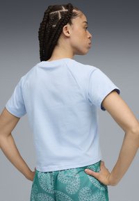 Camiseta corta de color azul claro en algodón suave, con un cuello redondo y mangas cortas, con una textura suave y costuras raglán.