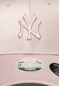Casquette de baseball em cetim rosa com um logótipo NY bordado na frente, com etiquetas de ajuste de tamanho na parte inferior da aba.
