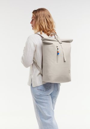 Zaino grigio a rotolo realizzato in materiale resistente all'acqua. Presenta spallacci regolabili, tasca con zip e un accento colorato sul tirazip.