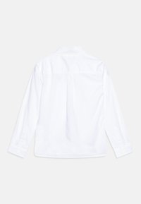 Camicia bianca a maniche lunghe con yoke posteriore e polsini con bottone. Realizzata in tessuto liscia, presenta un colletto classico e un design semplice.