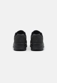 Black athletic shoes featuring a smooth synthetic upper, cushioned heel, textured accents, and a patterned rubber sole.