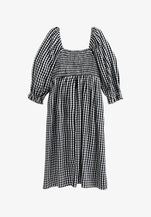 Vestido de cuadros en blanco y negro con escote cuadrado, cuerpo fruncido y mangas abullonadas. La textura de la tela es ligera y fluida.