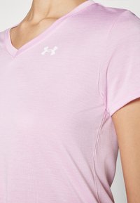 Lichtroze T-shirt met korte mouwen en V-hals ontwerp. Voorzien van een klein wit logo op de borst en een zachte, gladde textuur.