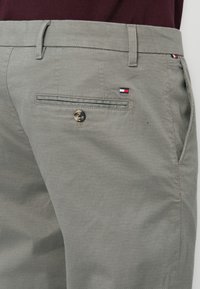 Grijze textuurbroeken met een knoopzak aan de achterkant en een klein tri-kleurig logodetail. Ontworpen met een klassieke pasvorm en een subtiele glans.