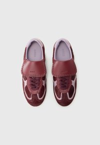 Maroon sneakers with a combination of leather and textured fabric, featuring a padded tongue, lace closure, and light purple insoles.