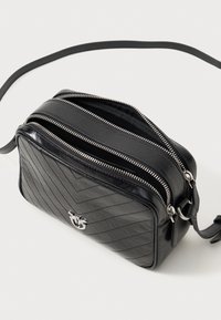 Černá kožená crossbody taška s prošívanou texturou, stříbrným kováním, dvojitými zipy a nastavitelným popruhem. Kompaktní obdélníkový tvar.