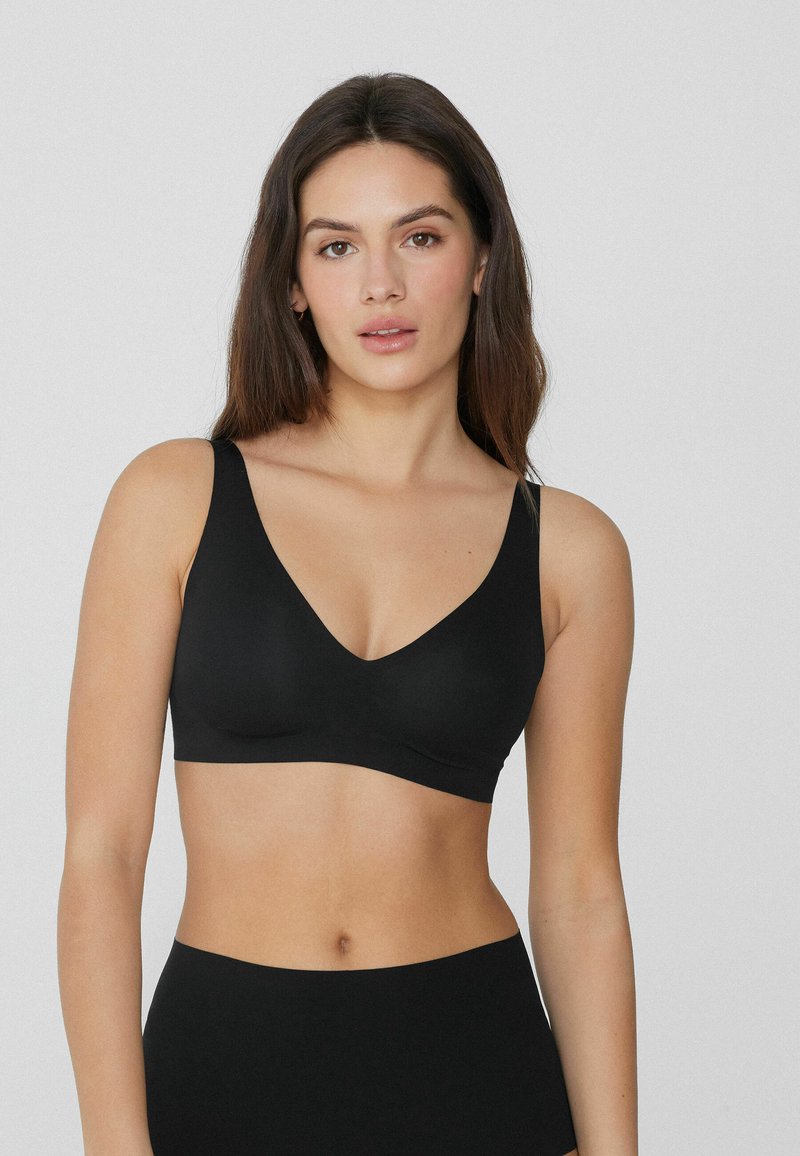 Soutien-gorge sans fil noir avec un décolleté en V profond, des larges bretelles et un tissu lisse. Son design sans coutures offre une apparence élégante et minimaliste.