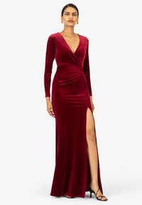 Langärmliges burgunderrot Samtkleid mit tiefem V-Ausschnitt, Wickeldesign und einem seitlichen Schlitz. Mit plissierten Details an der Taille.