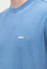 Φουτεράκι σε ανοιχτό μπλε χρώμα με στρογγυλή λαιμόκοψη, κατασκευασμένο από απαλό ύφασμα. Διαθέτει μικρό λευκό κεντημένο λογότυπο «obey» στην αριστερή πλευρά του στήθους.