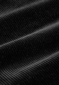 Black corduroy fabric with distinct vertical ridges, featuring a soft texture and smooth sheen, folded and slightly rumpled.