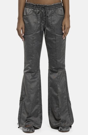 Ciemnoszare spodnie dzwony z wysokim stanem, dużymi przednimi kieszeniami, ściągaczem w talii i detalami w szwie bocznym, noszone przez stojącą osobę.