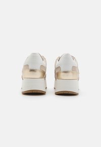 Baskets épaisses avec un dessus en daim beige et métal doré, accents blancs et une épaisse semelle blanche. Support dorsal texturé.