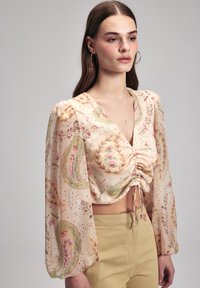 Leichte, pfirsichfarbige Bluse mit langen Puffärmeln, V-Ausschnitt, gerafftem Vorderteil und floralen Paisleymuster in Grün und Pink.