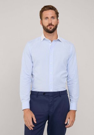Camicia a righe blu chiaro con colletto bianco e maniche lunghe, abbinata a pantaloni navy. Tessuto liscio con vestibilità su misura.