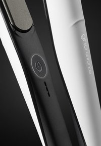 Zwart-witte stijltang met een textuur grip, aan/uit-knop en een strak ontwerp. Opvallend merkteken op het gebogen oppervlak.