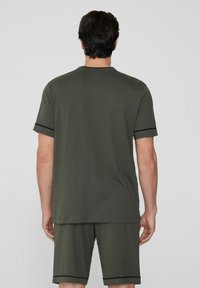Conjunto de camiseta y pantalones cortos de algodón verde oliva con cuello redondo, mangas cortas y ribete negro en los puños y el dobladillo.